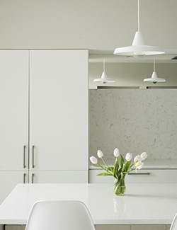 Modern, minimalist kitchen with white cabinetry and a central white table. Contemporary architect-designed interior.