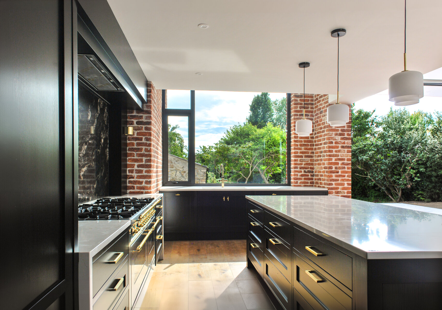 Contemporary kitchen with black cabinets, white marble counter and brass hardware