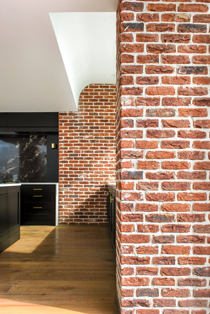 Brick piers flank the kitchen sink area with a dramatic scooped ceiling above