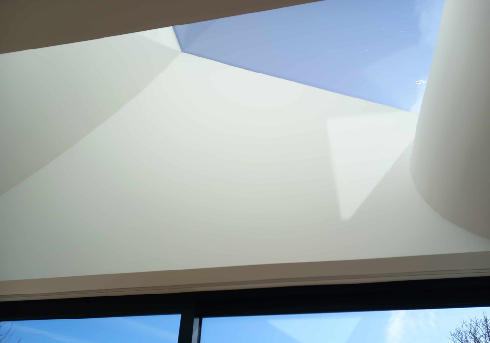 Curved plaster lightwell under sunny rooflight